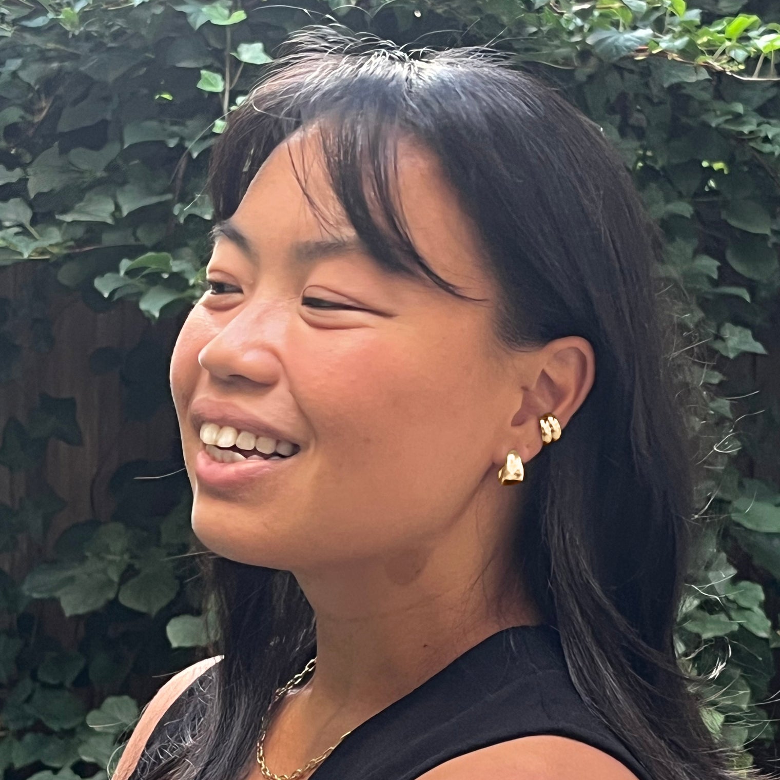 Close-up of a gold hoop earring, gold chain necklace and gold ear cuffs  on a model, highlighting its chunky and polished design. Perfect for adding a bold accent to any look.