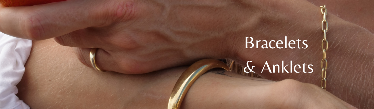 A bold gold cuff bracelet and a minimalistic chain gold bracelet
