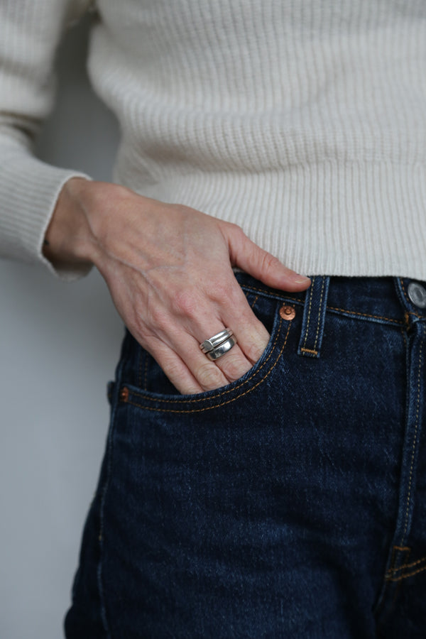 Human with two bold silver rings sliding into jeans
