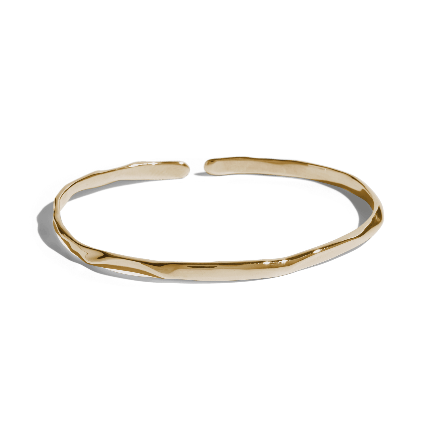 Gold cuff bracelet with a slim, uneven design, offering a minimalist and modern look. This jewelry packshot showcases the bracelet's unique texture and open-ended style