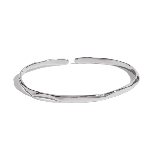 silver cuff bracelet with a slim, uneven design, offering a minimalist and modern look. This jewelry packshot showcases the bracelet's unique texture and open-ended style